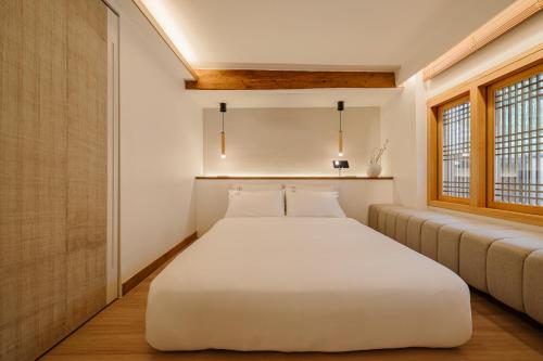 a bedroom with a large white bed and a couch at Luxury hanok with private bathtub - Happyjae in Seoul