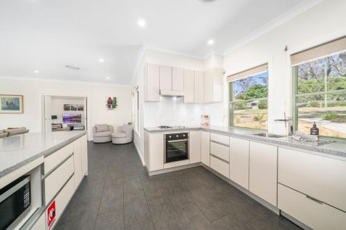 a kitchen with white cabinets and a large window at Cliffnest House in Katoomba
