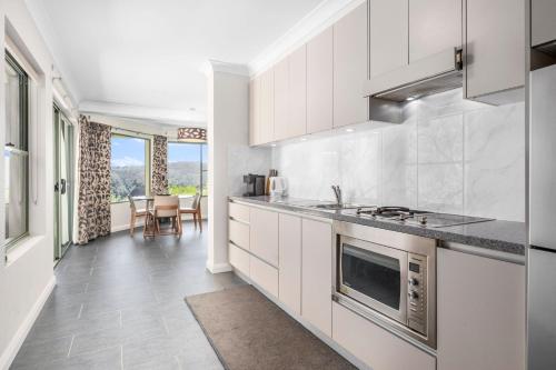a kitchen with white cabinets and a stove at Cliffnest House & Studio in Katoomba