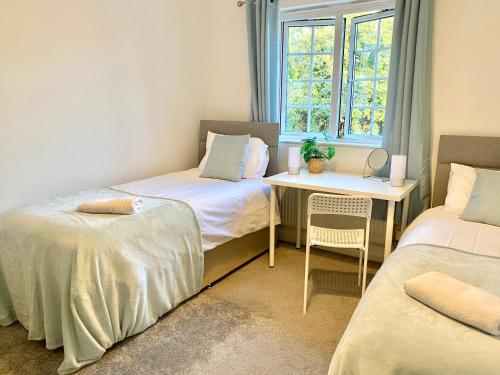 a room with two beds and a table and a window at Stunning Home Driveway and Garden FREE PRIVATE PARKING - Northampton in Northampton