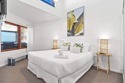 a white bedroom with a large bed and a window at Sea Spray - Lennox Head in Lennox Head