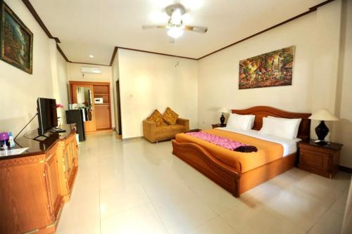 a bedroom with a bed and a couch and a television at Tori Inn in Sanur
