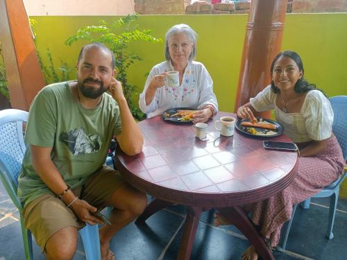 Abhi Homestay Hampi في هامبي: ثلاثة أشخاص يجلسون على طاولة لتناول الطعام