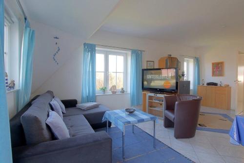 uma sala de estar com um sofá e uma televisão em KI22-15 Haus Seeadler em Dorum Neufeld