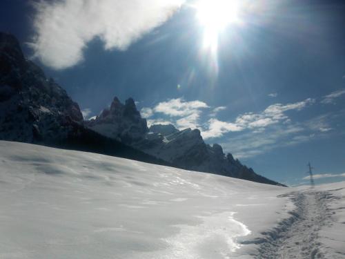 a snow covered mountain with the sun in the sky at Ski Residence in San Martino di Castrozza