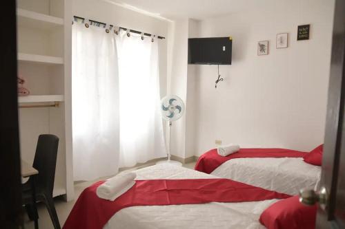een slaapkamer met 2 bedden met rode en witte lakens bij la casa del solo envigado in Envigado
