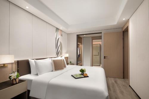 a bedroom with a large white bed in a room at Citadines Hope City Boao in Qionghai