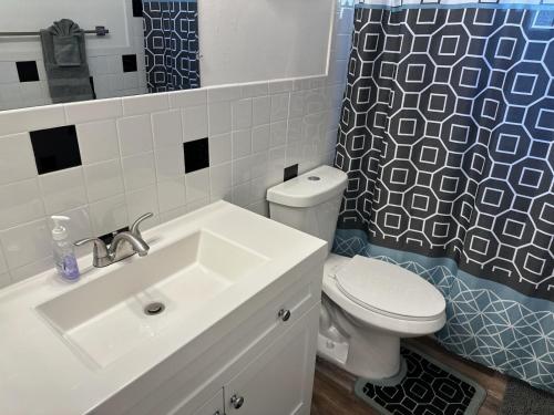 a bathroom with a sink and a toilet and a shower curtain at Whole House+Renovated+Pool+Lanai+BBQ+Close to All in West Palm Beach