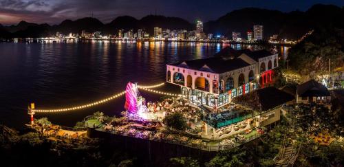 a large building with lights on the water at night at Le Pont Bungalow Cat Ba in Cat Ba