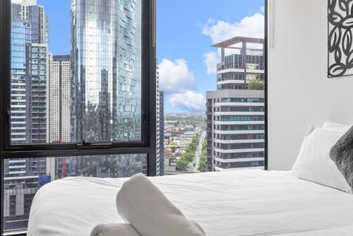 um quarto com uma cama branca e uma grande janela em Southbank Two Bedroom Apt - 2202 em Melbourne