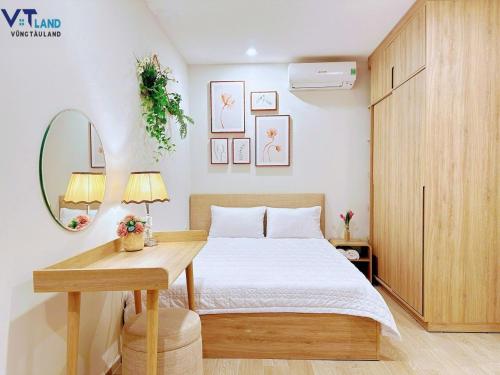 a bedroom with a bed and a table and a mirror at The Song Vung Tau Homestay - VTLand in Vung Tau