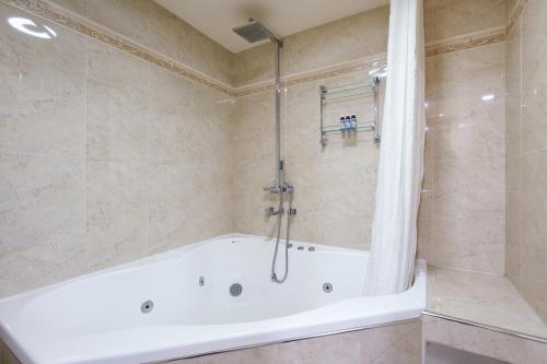 a white bath tub in a bathroom with a shower at Rydges Armidale in Armidale