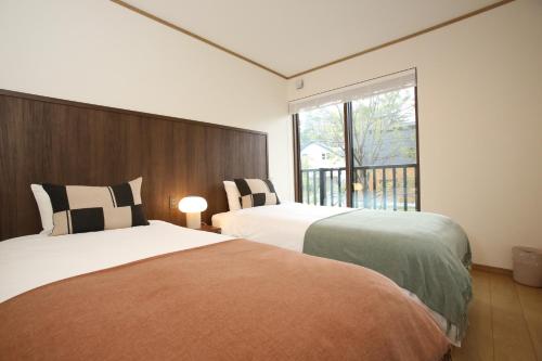 two beds in a room with a window at KAMATA SANSO in Hakuba