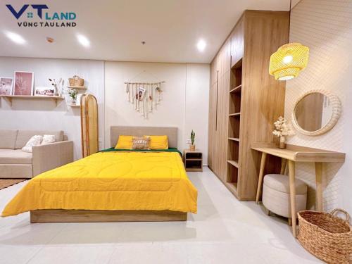 a bedroom with a yellow bed and a couch at The Song Vung Tau Homestay - VTLand in Vung Tau