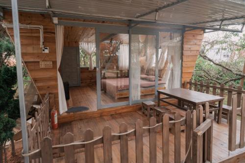 Cabaña de madera con mesa y cama en la cubierta en Mơ Garden Retreat DaLat, en Da Lat