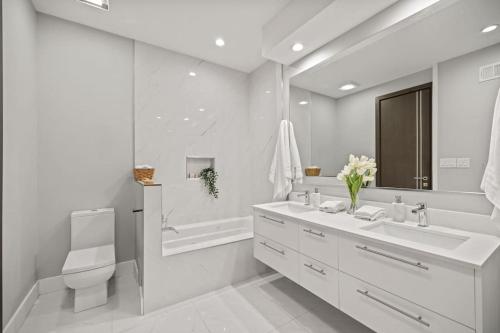 een witte badkamer met een wastafel, een toilet en een bad bij Luxury DC Penthouse w/ Private Rooftop! (Chapin 4) in Washington