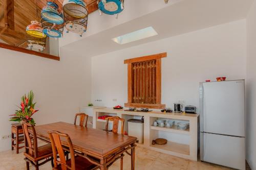 a kitchen with a wooden table and a refrigerator at Bali Ginger Suites & Villa in Seminyak