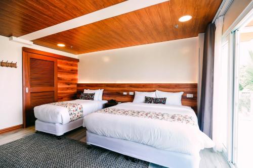 two beds in a bedroom with wooden walls and wood floors at Hotel Kimberly Tagaytay in Tagaytay