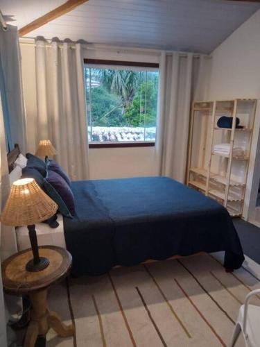um quarto com uma cama azul e uma janela em Caza di Zaia - kitnet em Búzios