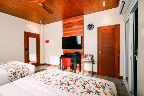 a bedroom with two beds and a flat screen tv at Hotel Kimberly Tagaytay in Tagaytay