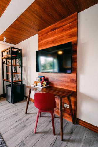 a table with a red chair and a television on a wall at Hotel Kimberly Tagaytay in Tagaytay