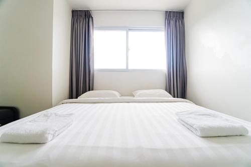 a white bed in a room with a window at Chequers Suites Subic Bay in Olongapo