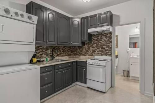 a kitchen with black cabinets and white appliances at Urban Chic Apartments Near Center City in Philadelphia