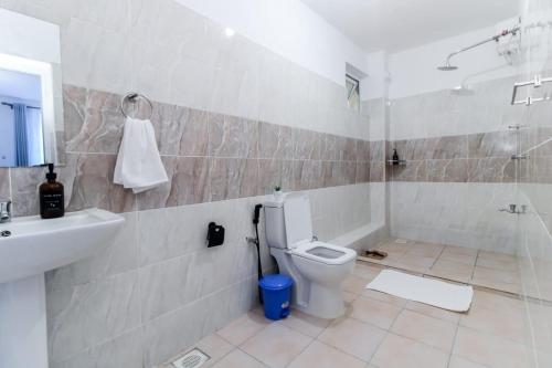 a bathroom with a toilet and a sink and a shower at Serene 3br Apartment in Nyali-Has Swimming pool and AC in Mombasa