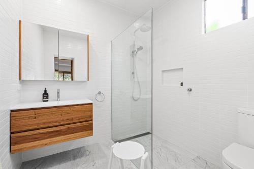 a white bathroom with a sink and a shower at Durras Cottage managed by Batemans Bay Accom in Durras