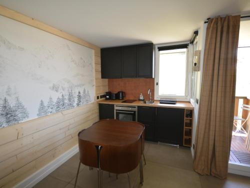 une cuisine avec des armoires noires et une table en bois dans l'établissement Studio rénové au pied des pistes avec balcon et cuisine équipée - FR-1-755-9, à Aime La Plagne
