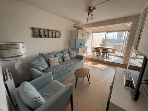 un salon avec un canapé bleu et une table dans l'établissement Appartement rénové 1 chambre + cabine, parking privé, à 400m de la plage - FR-1-81-601, à Port-Leucate