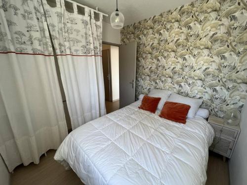 - une chambre avec un lit blanc et 2 oreillers rouges dans l'établissement Appartement rénové 1 chambre + cabine, parking privé, à 400m de la plage - FR-1-81-601, à Port-Leucate