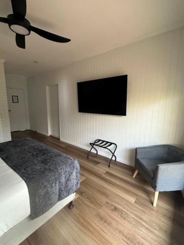 a bedroom with a bed and a chair and a flat screen tv at Burrum Tavern in Burrum Heads