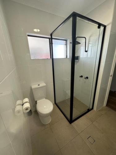 a bathroom with a toilet and a glass shower at Burrum Tavern in Burrum Heads