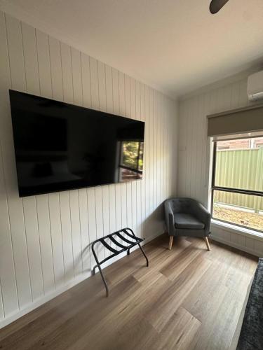 a living room with a chair and a flat screen tv at Burrum Tavern in Burrum Heads