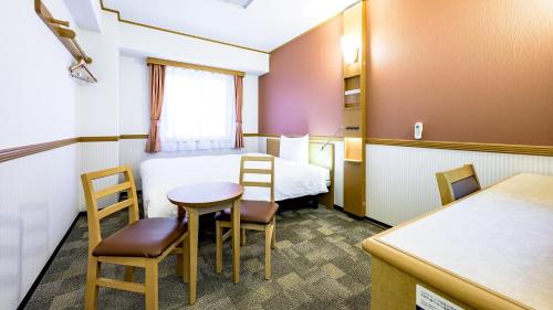 a small room with a bed and a table and chairs at Toyoko Inn Okayama eki Nishi guchi Migi in Okayama