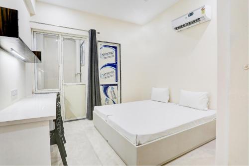 OYO Gaur Nitay في Dahmi: غرفة نوم بيضاء بها سرير ونافذة