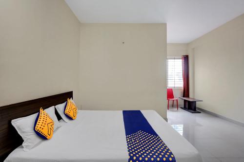 a bedroom with a bed with yellow and blue pillows at SPOT ON Capital Inn Hotel Rooms in Gundlupet