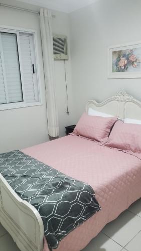 a bedroom with a bed with pink sheets and a window at Guarujá - Praia do Tombo - Apartamento in Guarujá
