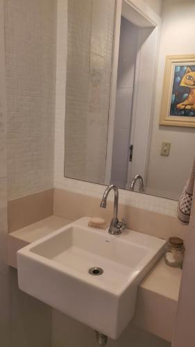 a white sink in a bathroom with a mirror at Guarujá - Praia do Tombo - Apartamento in Guarujá