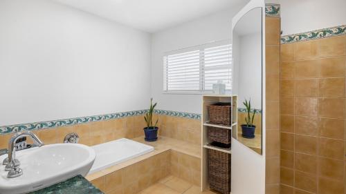 uma casa de banho com um lavatório e uma banheira em Beachfront Beauty em Whangaparaoa