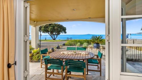 a table and chairs on a patio with a view of the ocean at Beachfront Beauty in Whangaparaoa