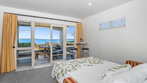 a bedroom with a bed and a view of the ocean at Beachfront Beauty in Whangaparaoa
