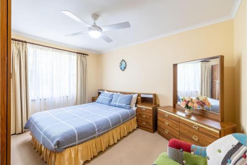 a bedroom with a blue bed and a mirror at 3 Tomaree Street - Spacious 4 bedroom house with air con situated in the heart of Nelson Bay in Nelson Bay