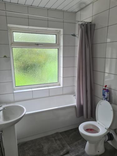a bathroom with a toilet and a sink and a window at L & J ESCAPES-4 BEDROOMs SUITABLE FOR CONTRACTORS AND FAMILIES- LARGE PRIVATE PARKING-10 MINUTES TO M6 JUNCTION 9 in Coseley