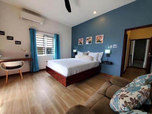 een slaapkamer met een bed met blauwe muren en een bank bij 'The Solace' New Luxury Modern 1Bed 1Bath Apt. in Portmore