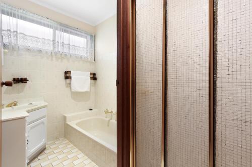 a bathroom with a tub and a sink and a shower at Family Escape in Lakes Entrance