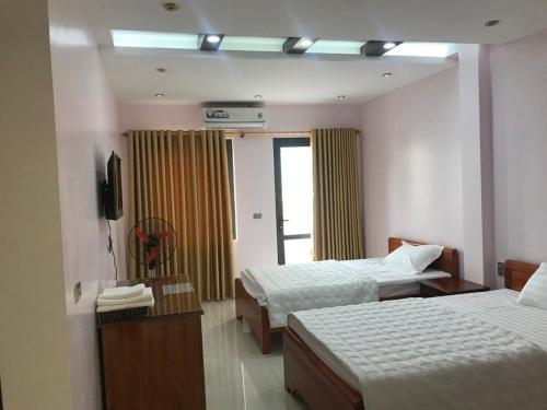 una camera d'albergo con due letti e una televisione di Quỳnh Hương Hotel Phú Thọ a Phú Thọ