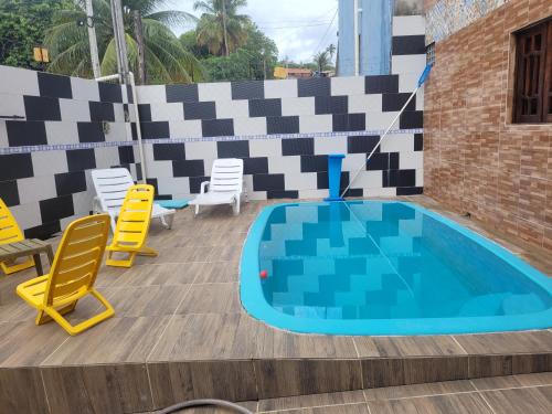 a swimming pool with yellow chairs and a table and chairs at Casa de praia in Goiana
