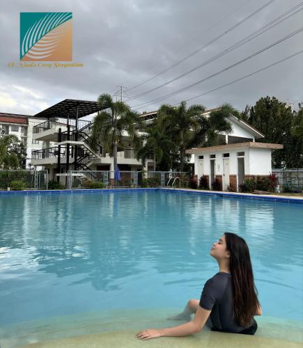 una mujer sentada en el borde de una piscina en El Nissi Family Cabin (Condo Beside Enchanted Kingdom), en Santa Rosa